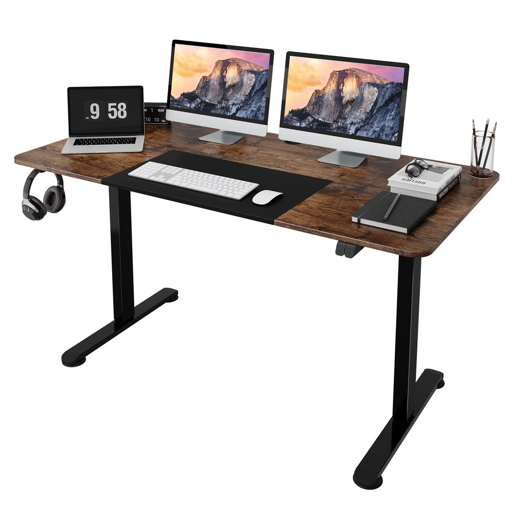 Wooden standing desk with dual monitors, keyboard, mouse, headphones hanging on left, and desk accessories